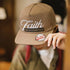 Beige cap with 'Faith' and 'Action' logos, worn by a person.